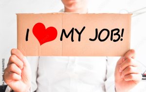 An individual holding a sign that says "I heart my job." 